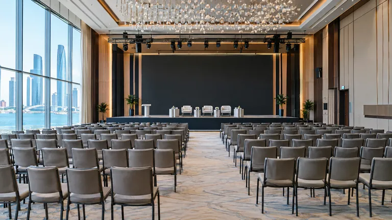 An empty, modern conference hall in Abu Dhabi with rows of chairs facing a stage