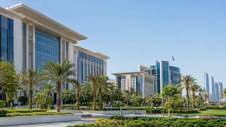 Modern government office buildings in Abu Dhabi with landscaped gardens and palm trees