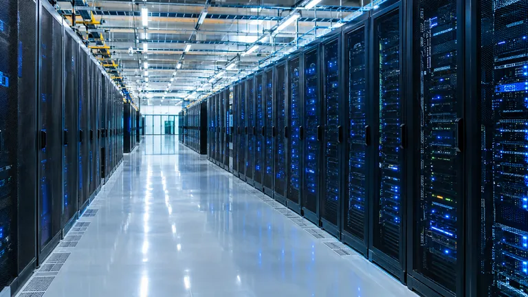 A long, brightly lit data centre hall with rows of server racks and blue indicator lights
