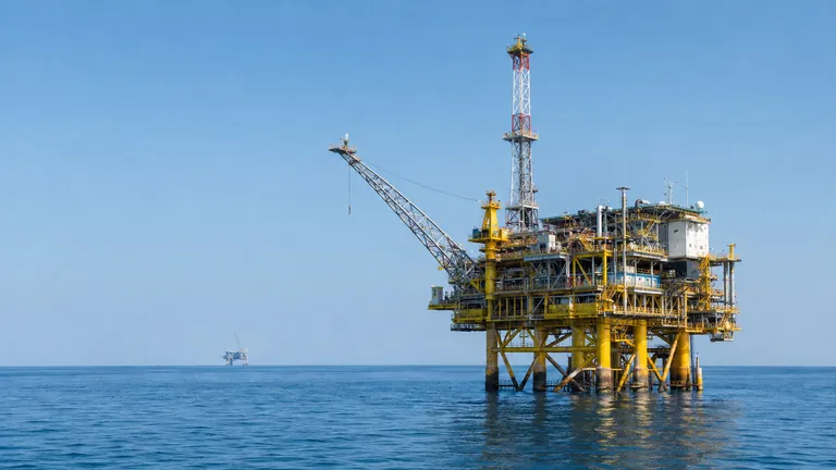 An offshore oil platform in calm blue Gulf waters under a clear sky